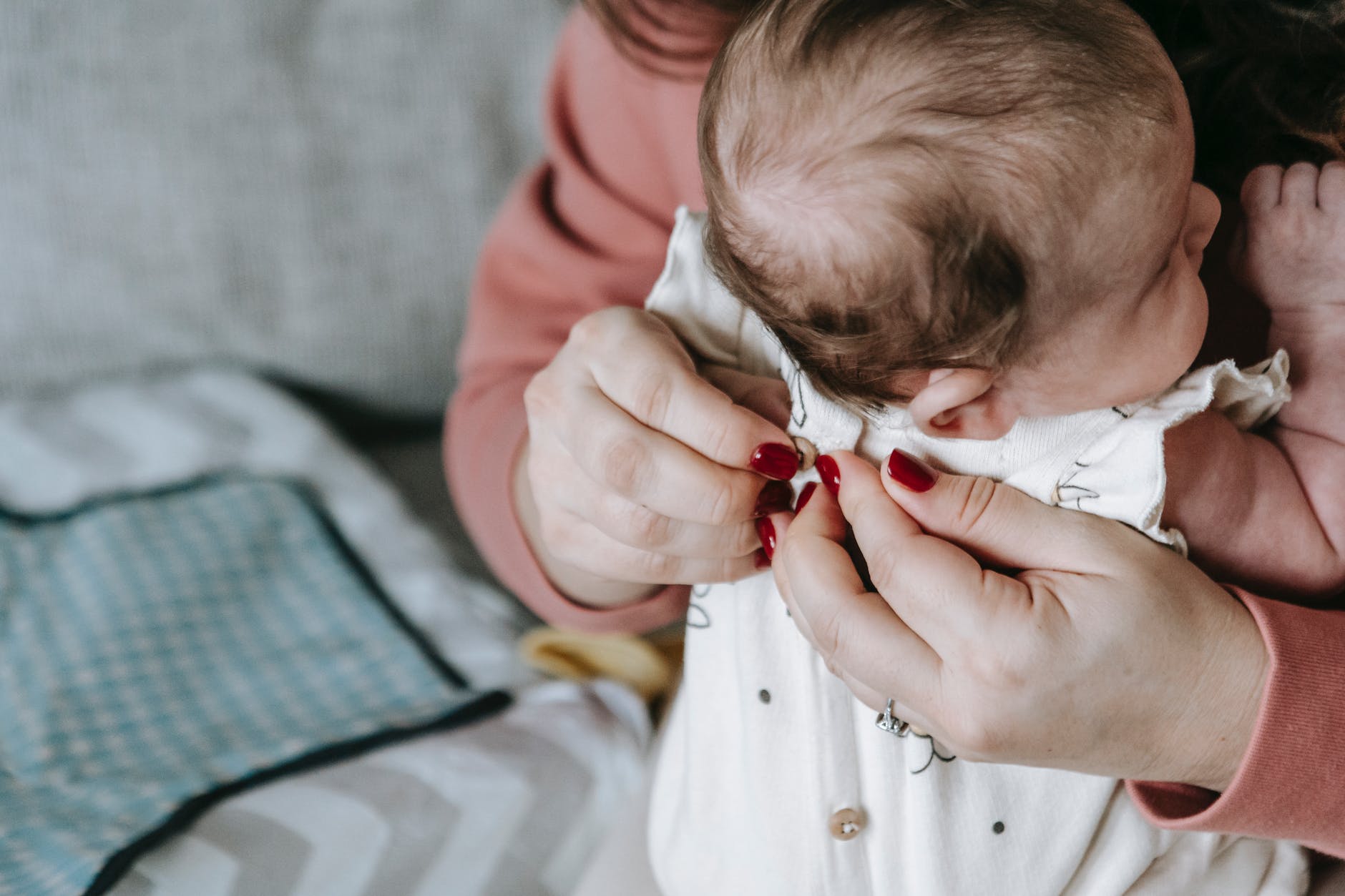 person putting clothes on a baby